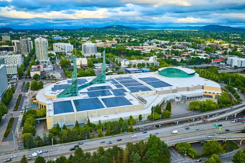 Downtown Portland, Oregon with convention center in foreground with green glass spires and rooftop solar panels visible.